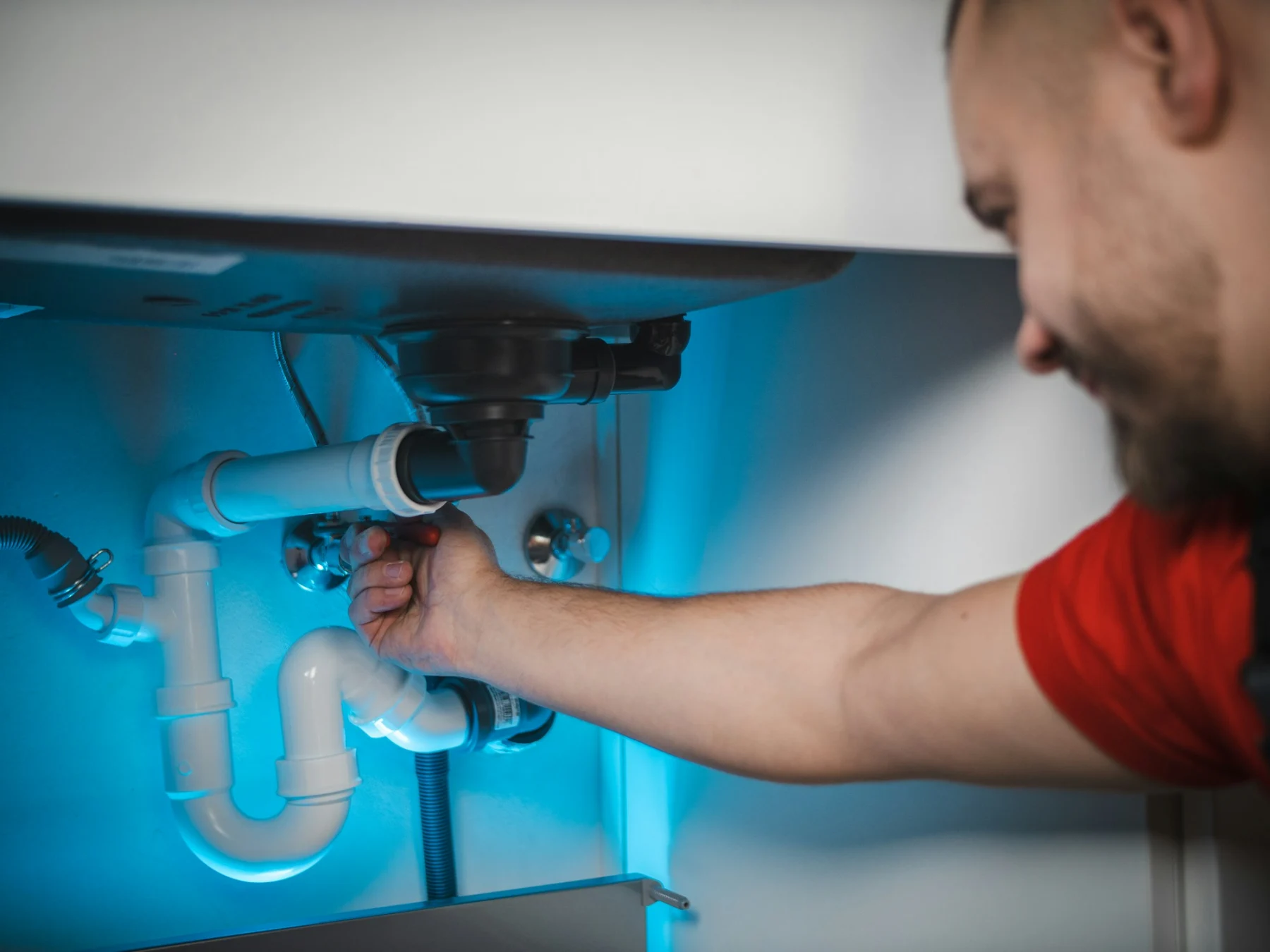 Sanitärfachkraft bei der Reparatur unter einem Waschbecken